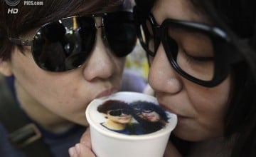 A couple drinks a cup of latte with their picture printed on top of the milk foam at a Family Mart in Taipei