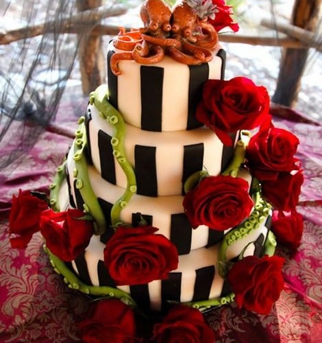 Полосатыq свадебный торт, украшенный двумя влюбленными осьминогами