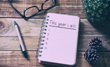 New Year Resolutions List on Notepad on Top of Wood Desk
