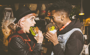 Funky couple eating burger in the pub