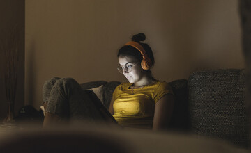 Woman with headphones listening to music on couch at home